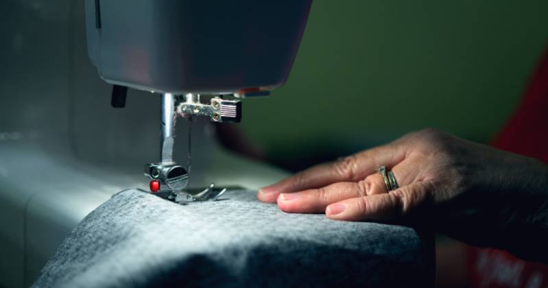 Sewing maching and blue fabric, hand pushing it through